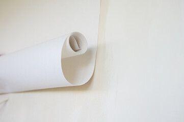 A roll of white wallpaper. Attaching wallpaper to the wall.