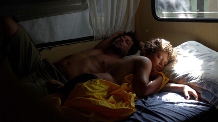 Fototapeta na wymiar Single father and son 9 years old sleeping in a camper - wake up in the morning - lifestyle and parenthood - happiness and family holidays 