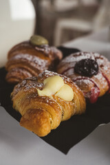 Plate with a variety of fresh filled croissants on white table indoors, closeup. 