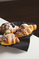 Plate with a variety of fresh filled croissants on white table indoors, closeup. 