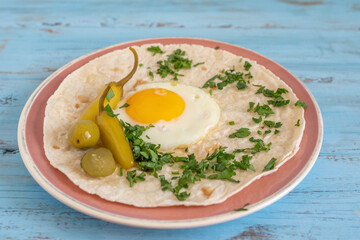 Fresh herbs, sunny side up egg, pickled vegetables on tortilla bread.