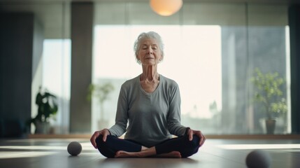 In serene yoga studio, European woman in eldery years enters into deep meditative state. Psychological theories like embodied cognition describe experience physical movement spills