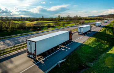 Large Transportation Trucks departing on a highway road through the countryside with a beautiful blue sky