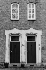 Black and white version of a historic facade with twin doors and windows entirely in symmetry.