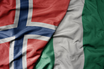big waving national colorful flag of norway and national flag of nigeria .