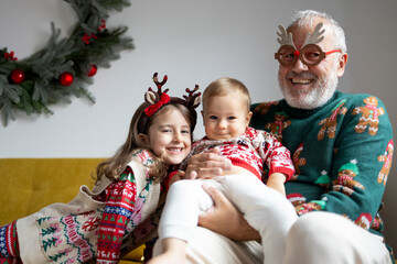 Funny portrait of mature father with two children celebrating christmas at home