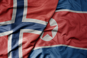 big waving national colorful flag of norway and national flag of north korea .