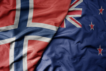 big waving national colorful flag of norway and national flag of new zealand .