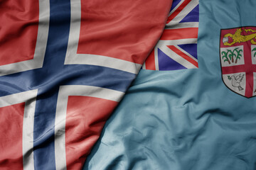 big waving national colorful flag of norway and national flag of Fiji .
