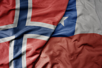 big waving national colorful flag of norway and national flag of chile .