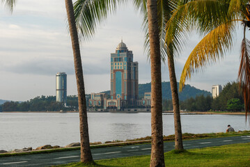 A view of Kinabalu Tower, also known as Sabah State Administrative Center, from a park with palms...