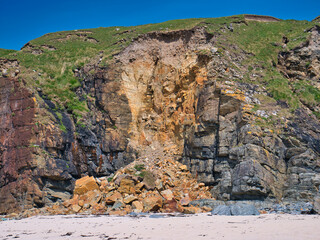Rock strata are visible above rock debris after a coastal land slip on a beach near the Butt of...