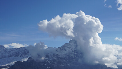 Fototapeta na wymiar A big cloud pushing against a huge snowy mountain