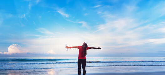 Asian women jogging workout on the beach in the morning. Relax with the sea walk and drinking water from the plastic bottles