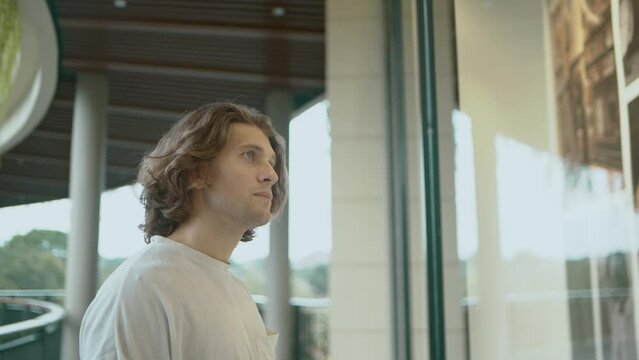 Young attractive man looking at shop window in the mall