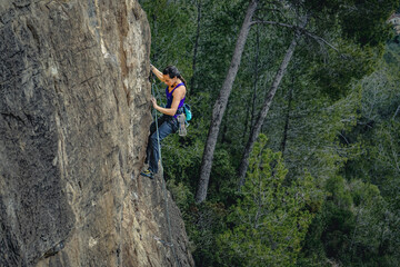 Obraz premium Forest Adventure: Black-Haired Woman Scaling a Challenging Cliff