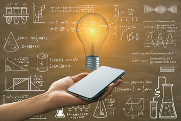 Close up of female hand holding smartphone with glowing light bulb on chalkboard wall background with mathematical formulas. Science, idea and education background.