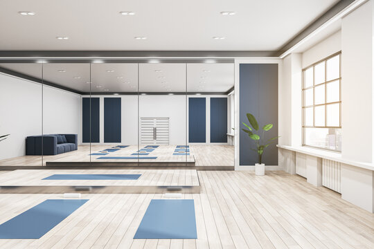 Bright group class in gym interior with blue yoga mats, wooden flooring, mirror with reflections, window with city view and daylight. 3D Rendering.