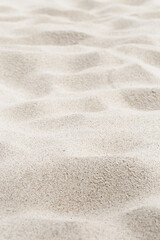 Fototapeta na wymiar Fine Sand texture natural view. Close up of sand on shore sea, white waves dunes, beige neutral color, minimal nature aesthetic vertical photo. Sandy beach for background, selective focus