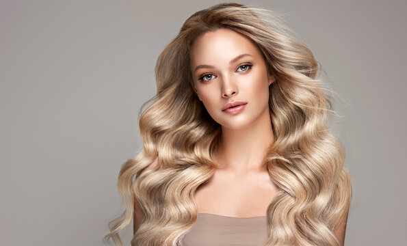 Beautiful smile  blonde model  girl  with long curly  hair . Smiling blond  woman hairstyle wavy curls .     Fashion , beauty and makeup portrait
