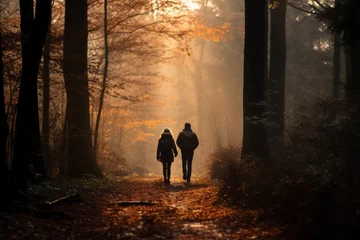 Tuinposter a couple walking on a forest road in an autumn morning © urdialex