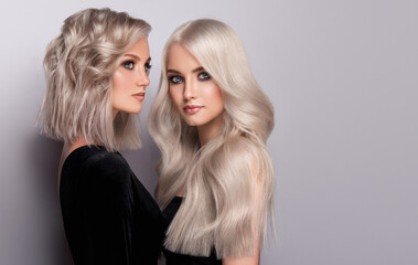 Two beautiful girls with hair coloring in blond. Stylish hairstyle curls done in a beauty salon. Beauty, cosmetics and makeup - 646079839