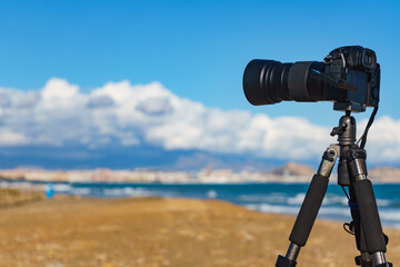 Camera taking picture of sea coast landscape - obrazy, fototapety, plakaty