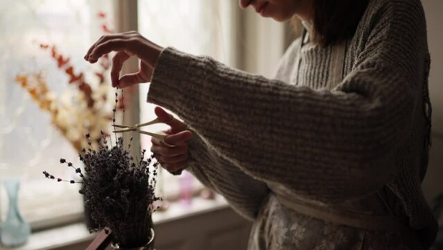 Close up of woman hands who cuts a sprig of lavender with scissors for decoration at cozy home Unsurpassed pre-holiday atmosphere and home comfort Homemade concept