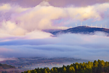 Foggy valley and wind turbines in clouds