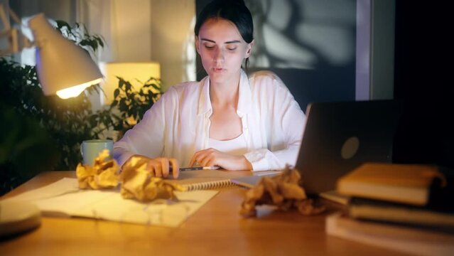 Overworked tired woman freelancer or student with severe neck back shoulder pain after hard work on laptop computer stretching and ties to pull muscles at home workplace at late night indoors