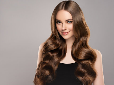 Beauty girl with long and shiny wavy hair . Beautiful woman model with curly hairstyle .
