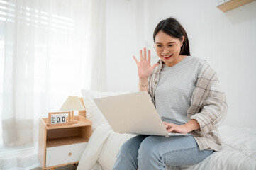 Asian girl freelance translator who is happy to work She is working on a laptop. In her bed...