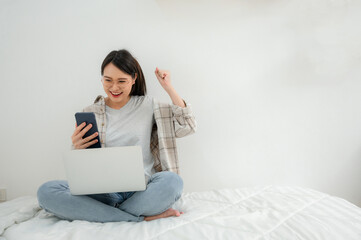 A girl working freelance relaxed lifestyle at home using laptop computer and phone call to educate or study. Asian woman typing on keyboard surfing internet