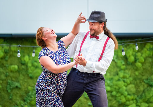 Portrait of cheerful couple dressed in vintage clothes dancing retro swing dance which was very popular during West Coast Swing era in 1920-40s. They are smiling, laughing having good time together.