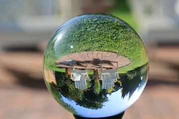 Blick durch eine Glaskugel in einen Hausgarten im Sommer