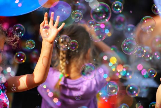 Small children play with soap bubbles in the summer outdoors. Happy childhood concept.