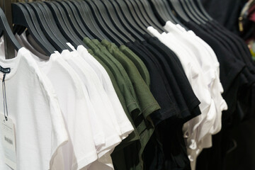 A collection of pastel-colored T-shirts hanging on a clothes rack on a counter in a store.