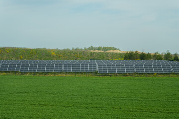 Solar panels of the power plant on the background of a green field