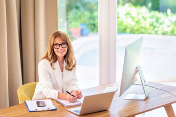 Blonde haired businesswoman sitting at her desk and working on her laptop