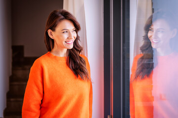 Attractive mid aged woman relaxing at home by the window