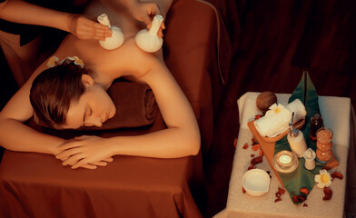 Hot herbal ball spa massage body treatment, masseur gently compresses herb bag on woman body....