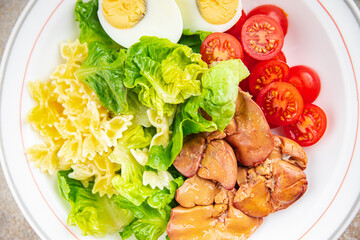 salad chicken liver, pasta salad , tomato, green leaf lettuce, boiled egg, farfalle snack meal food on the table copy space food background rustic top view