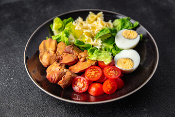 Fototapeta na wymiar salad chicken liver, pasta salad , tomato, green leaf lettuce, boiled egg, farfalle snack meal food on the table copy space food background rustic top view