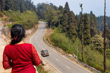 Female tourist enjoys an aerial view of mountain highway road with scenic landscape at Lava in the...