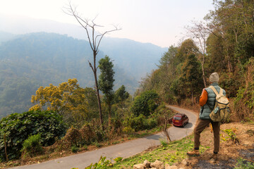 Male tourist enjoys an aerial view of a mountain road amidst scenic Himalaya mountain landscape near Tinchuley, a scenic hill station at Darjeeling, India