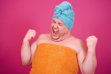 Early morning. Funny fat man after a shower getting ready for a party. Pink background.