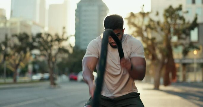 Training, fitness and man with battle ropes in a city for bodybuilding, power and intense cardio. Heavy rope, resilience and guy athlete outdoor for muscle development, endurance and body workout