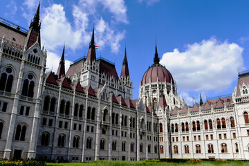 Fototapeta na wymiar exterior closeup detail of the Hungarian Parliament in Budapest. stone building in neo gothic style. popular travel destination and landmark building. European tourism. dynamic blue sky. white clouds