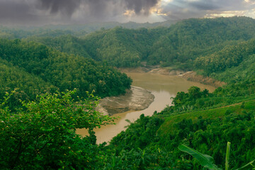 During the rainy season, the thick green hills blend into the thick black clouds in the sky. Sangu river flows below. Hilly region of Bandarban district of Bangladesh. - obrazy, fototapety, plakaty