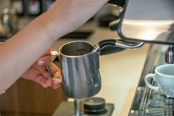 A young female barista making a delicious cappuccino